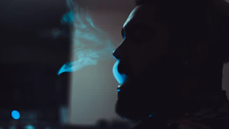 Profile shot of a fighter exhaling in slow motion, illuminated by electric blue light.