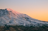 A fierce dragon soaring over snow-capped mountains at sunset.