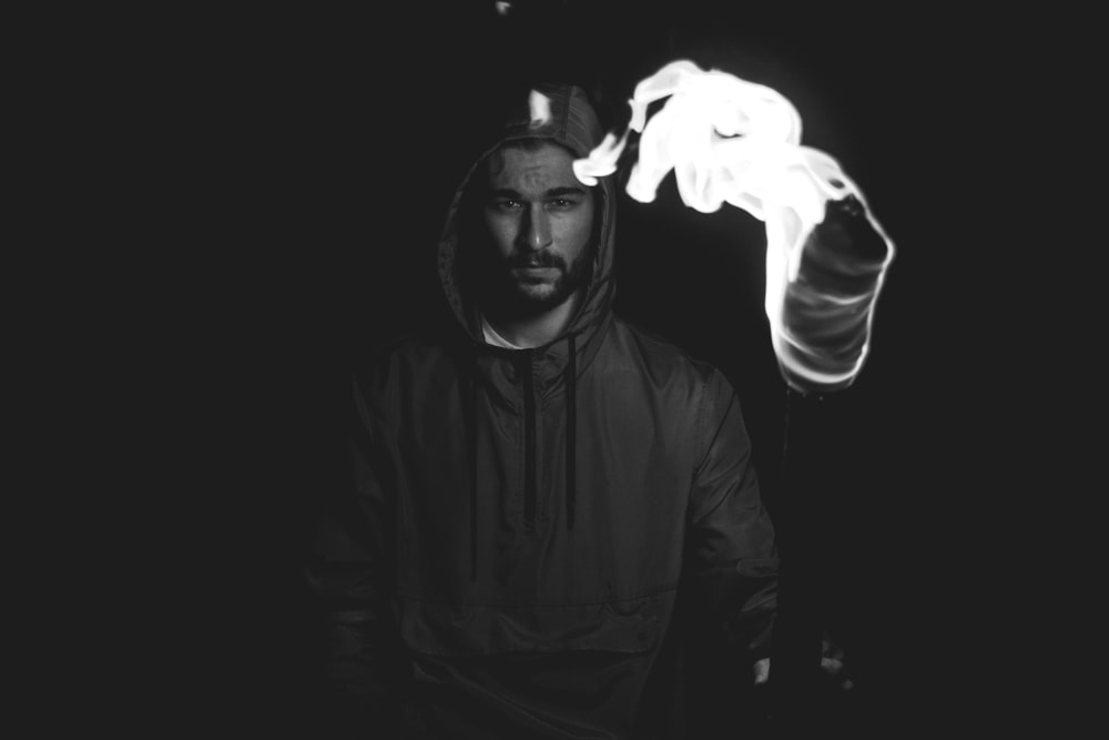 grayscale shot of man holding torch