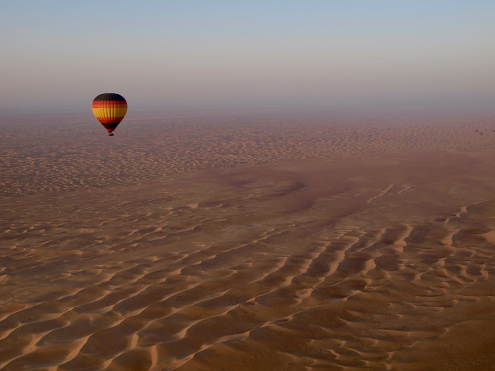 Schwarzer, roter und gelber Heißluftballon fliegt am Himmel