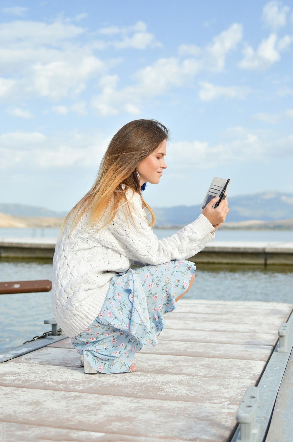 mulher usando o smartphone enquanto sentada da doca durante o dia