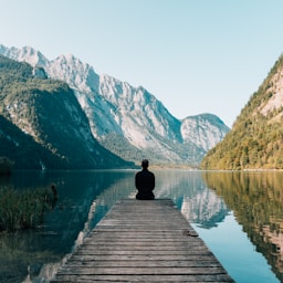 man sitting on gray dock