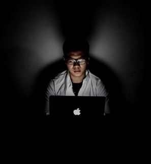 man using MacBook inside dark room