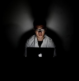 man using MacBook inside dark room