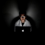 man using MacBook inside dark room