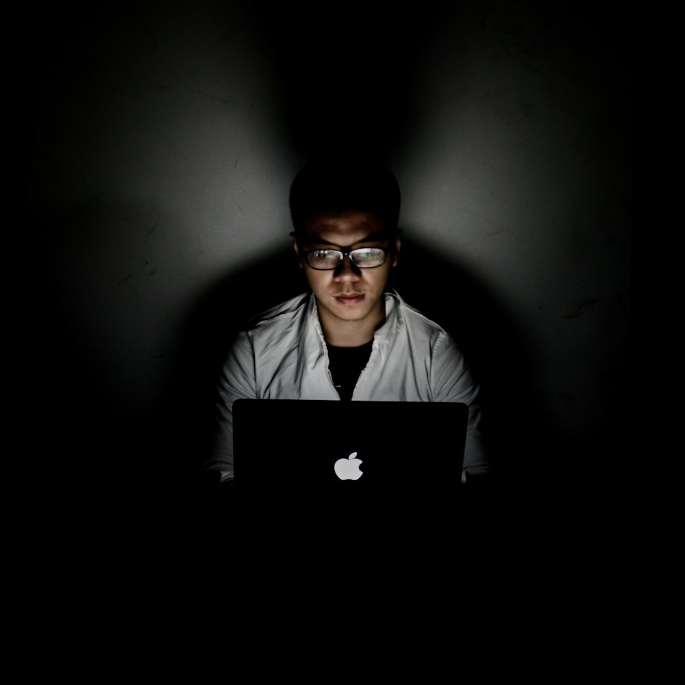 Mann mit MacBook in dunklem Raum