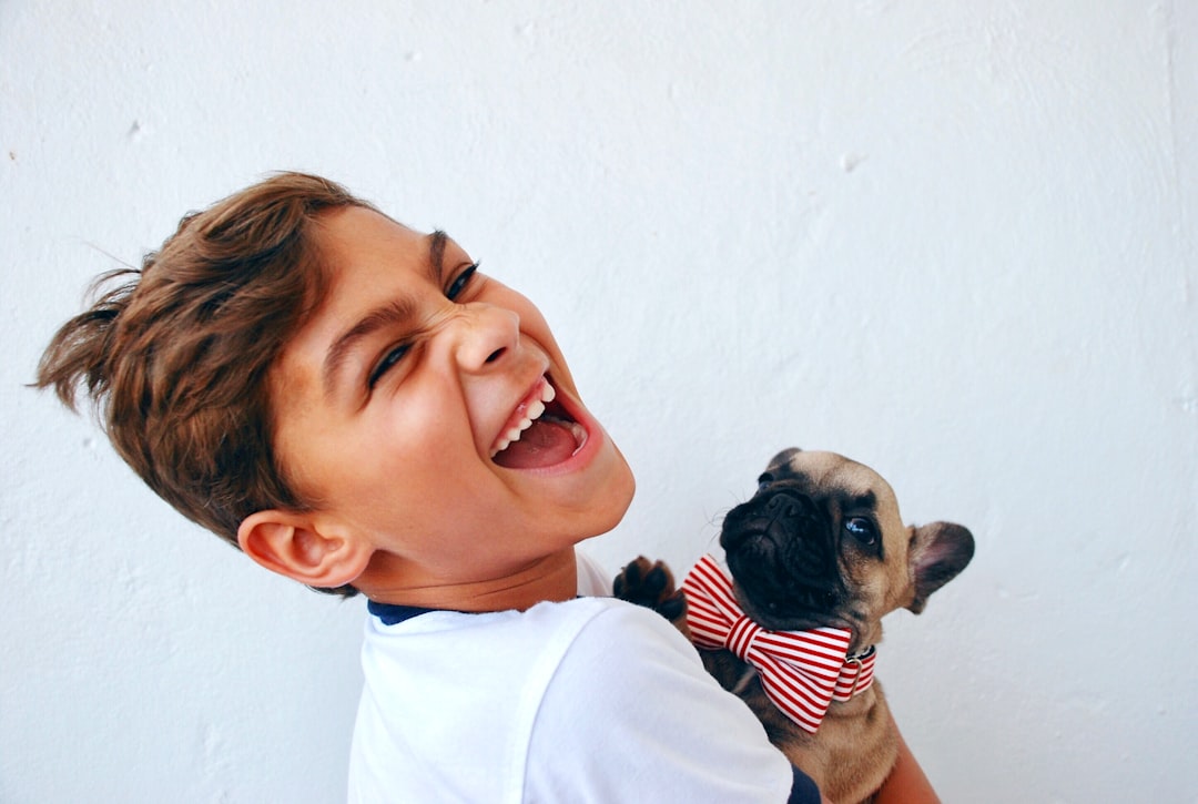 menino rindo e segurando cachorro de gravata engraçado