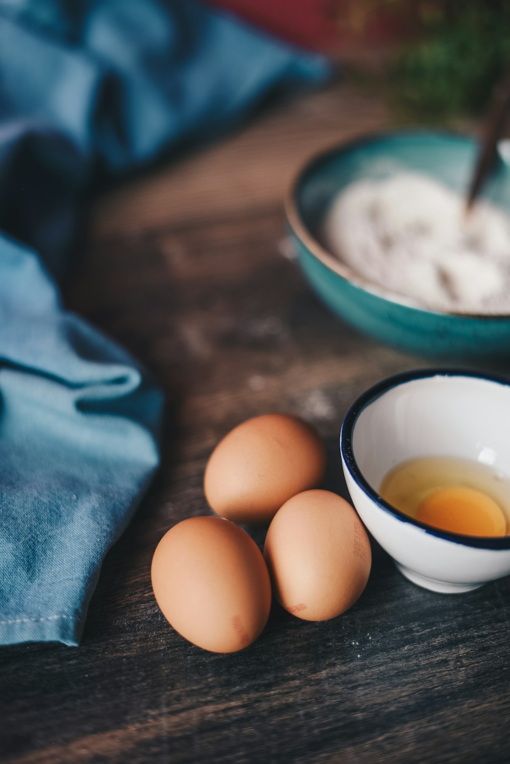 Fotografía de enfoque selectivo de tres huevos marrones cerca de un cuenco de cerámica blanca