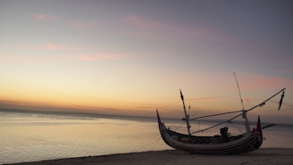 A traditional Sri Lankan fishing boat resting on the calm waters of the southern coast at sunset.