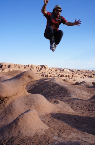 man jumped on desert during daytime