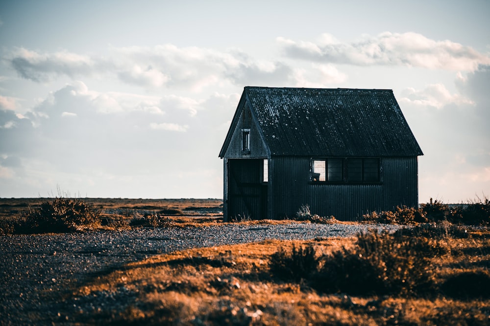 white hut on deserted land under white clouds during daytime