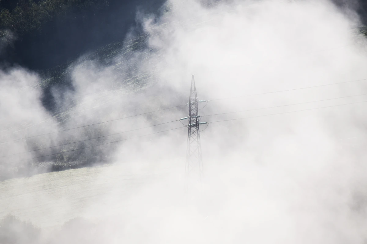 Steel electricity transmission tower against a cloudy sky