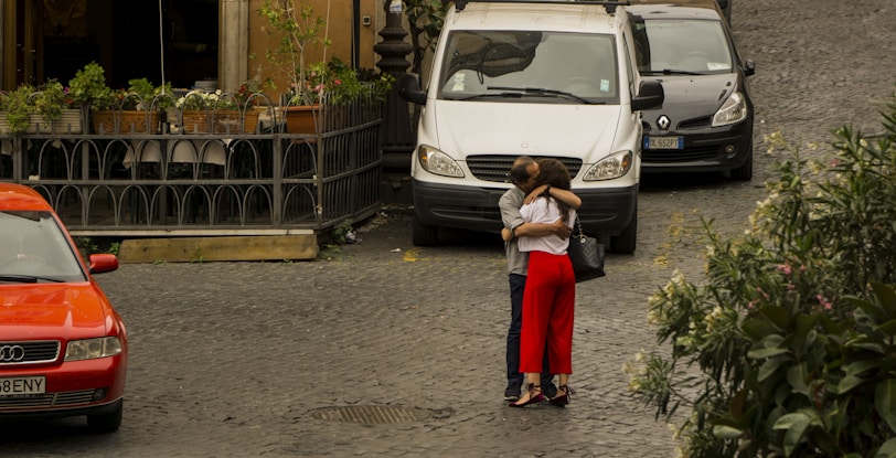 Katie and Dan smiling beside their van in a bustling European street market.