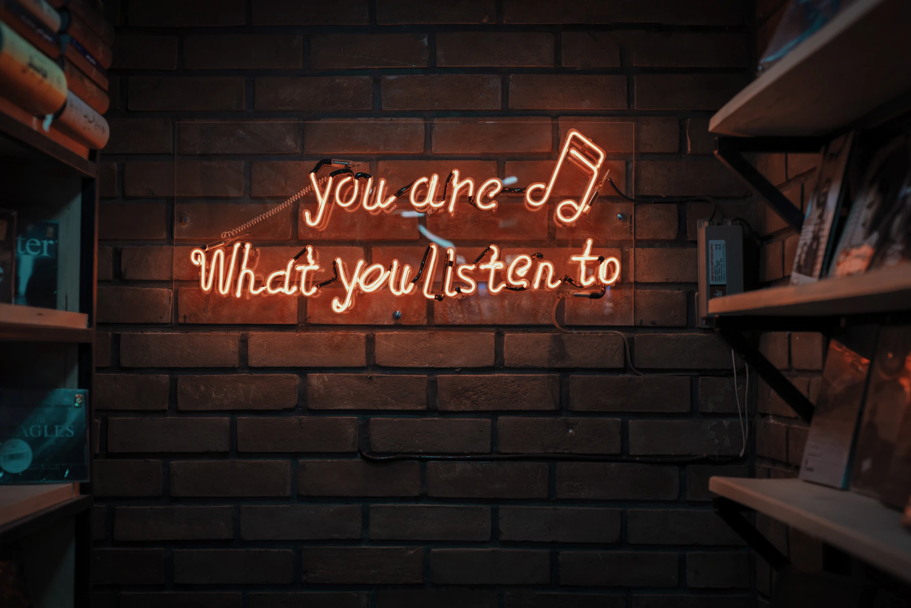 Neon sign with music lyrics against a brick wall