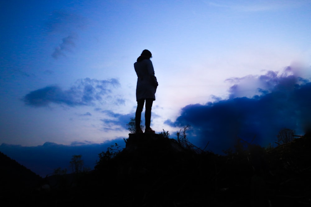 Person, die in der Dämmerung auf einem Felsbrocken steht