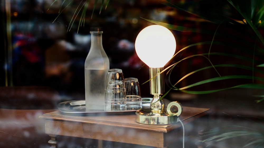 selective focus photography of lamp and bottles with glassware
