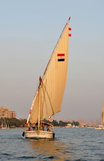 A serene sunrise over the Nile River with a traditional felucca boat gently sailing by.