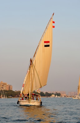 A felucca boat gently sailing on the Nile River near Luxor under a clear blue sky.