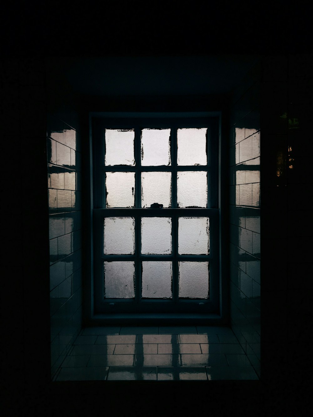 Una ventana en una habitación oscura con luz entrando