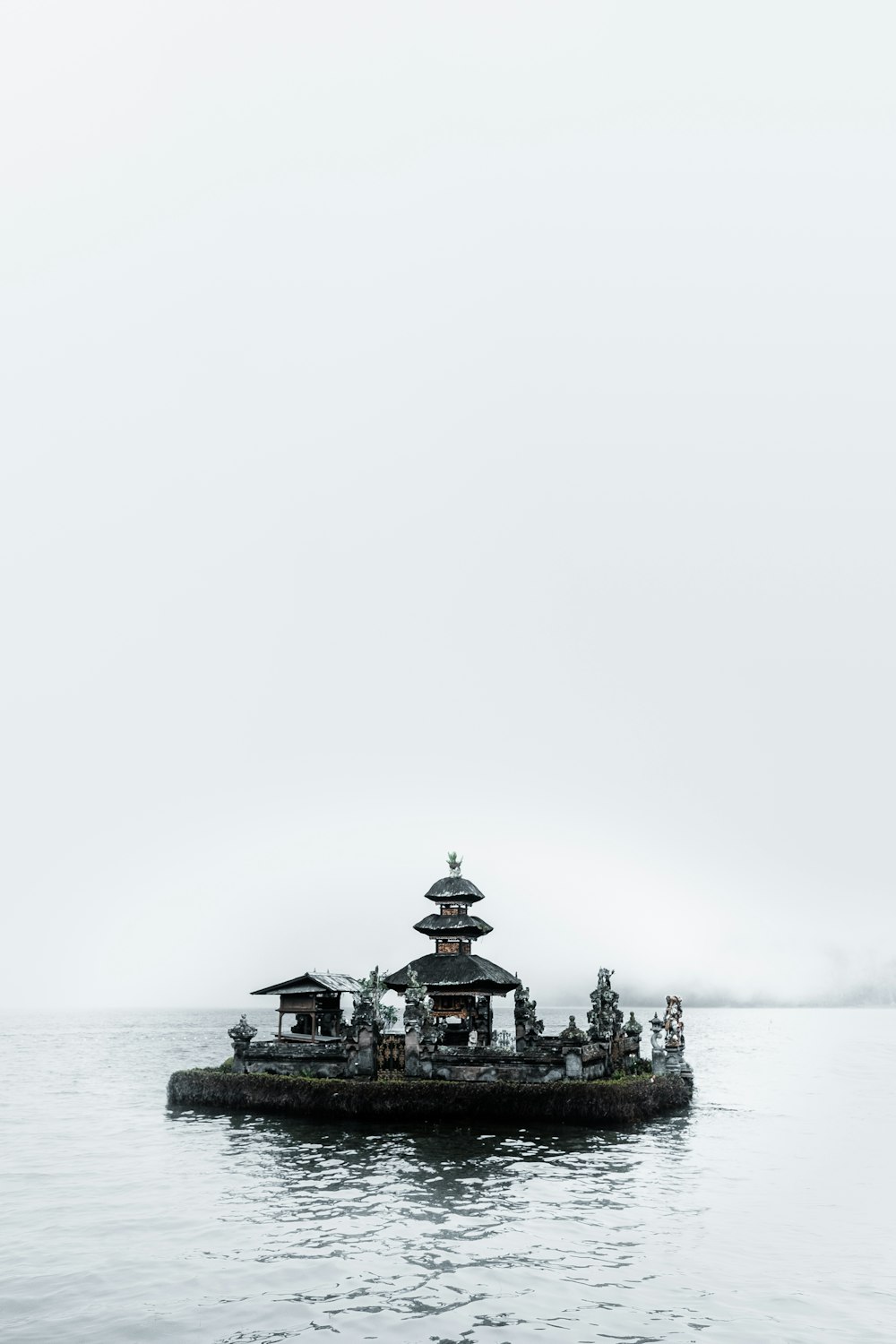 Schwarz-brauner Tempel umgeben Meer unter grauem Himmel