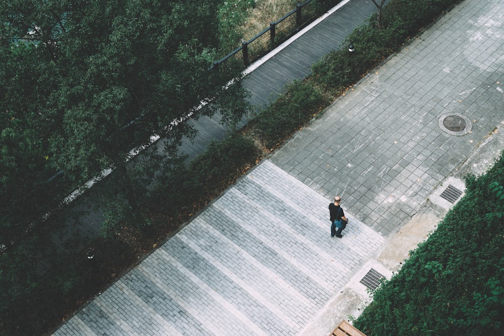 a man walking down a sidewalk next to a forest