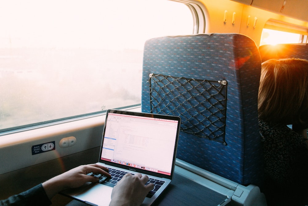 person using macbook pro on blue and white chair