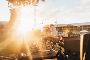 photo of music band performing at front of crowded stadium under blue sky