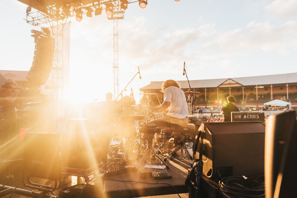 photo of music band performing at front of crowded stadium under blue sky