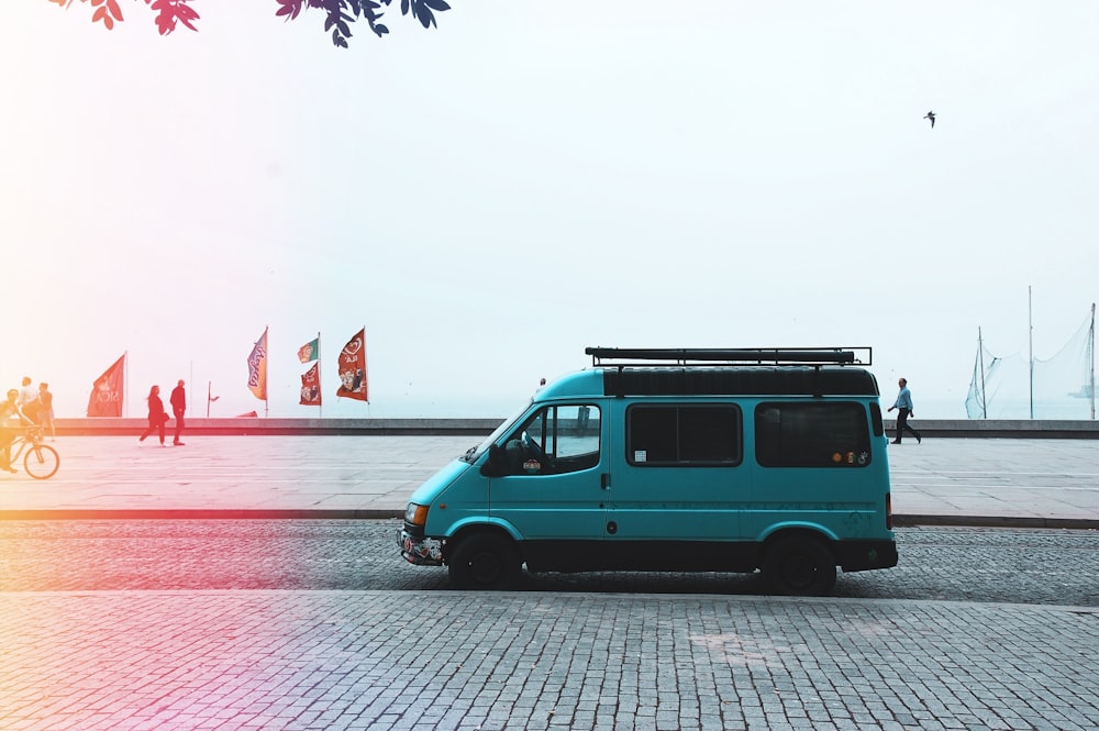 teal van on gray asphalt road