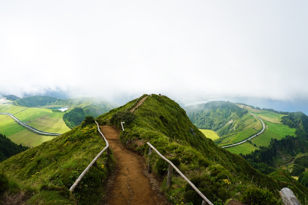 pathway in the middle of hill under cloudy sky