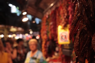 A warm-toned photo of dried chili peppers hanging in a traditional spice market.