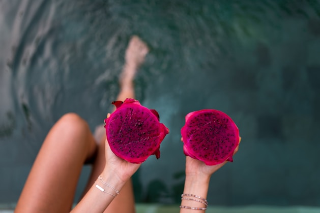person holding two pink fruits