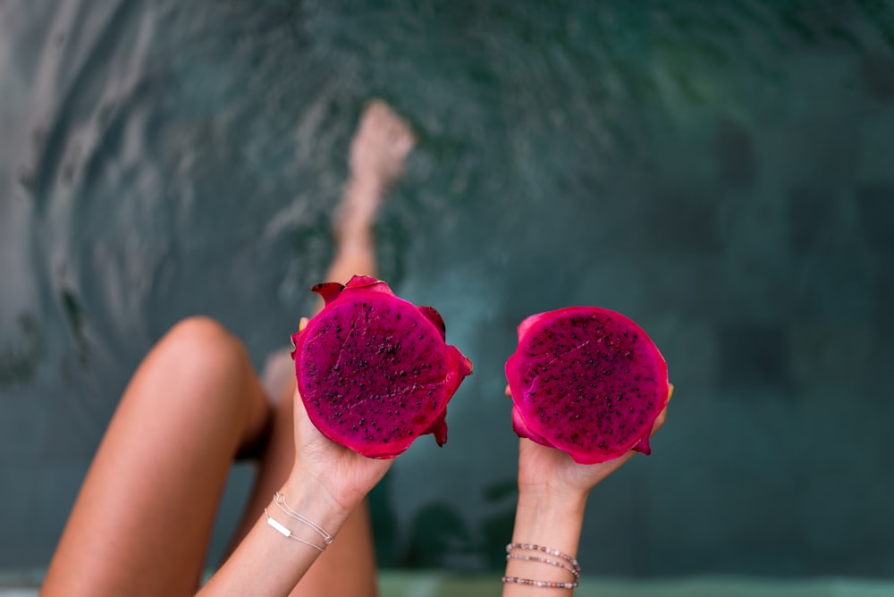 person holding two pink fruits