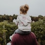photo of girl riding on person shoulder
