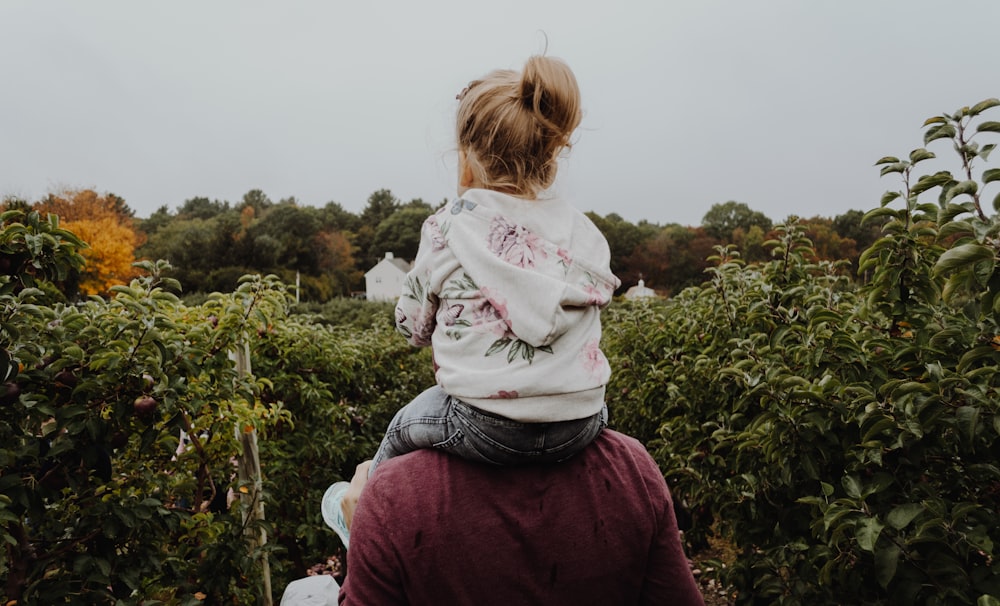 photo of girl riding on person shoulder