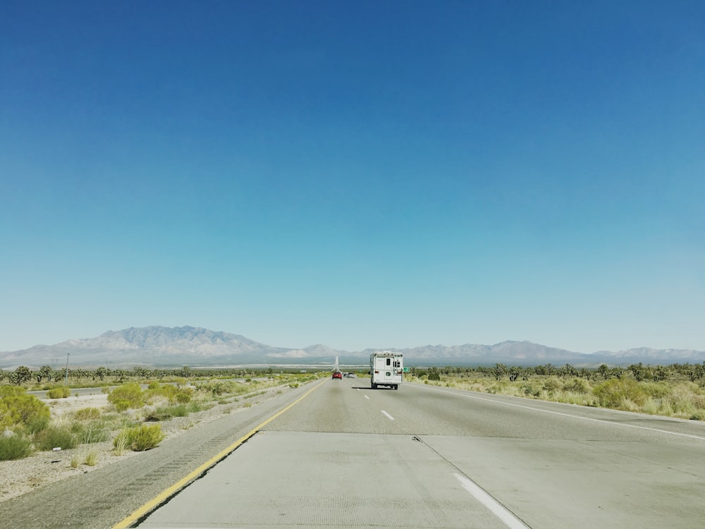 Auto bianca sulla strada grigia sotto la fotografia del cielo blu