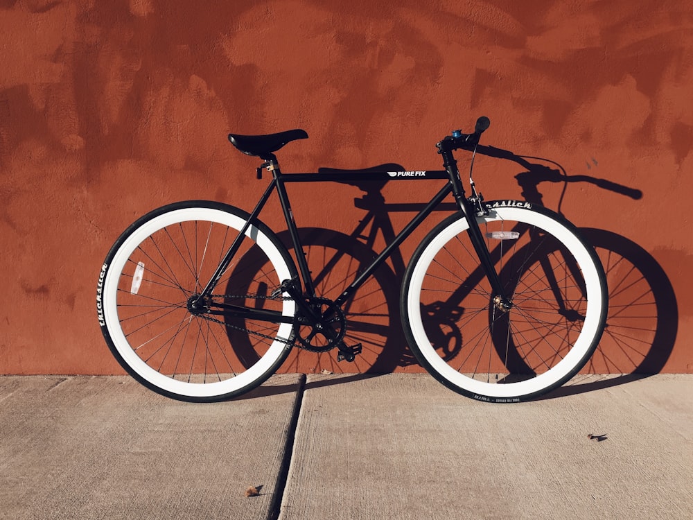 bicicleta de montanha preta e branca perto da parede marrom