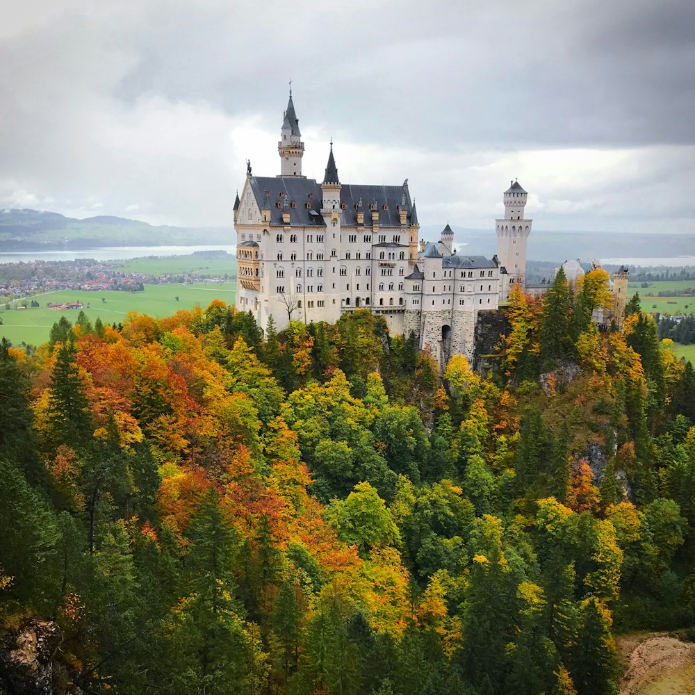 Castillo de hormigón blanco rodeado de árboles bajo el cielo blanco durante el día