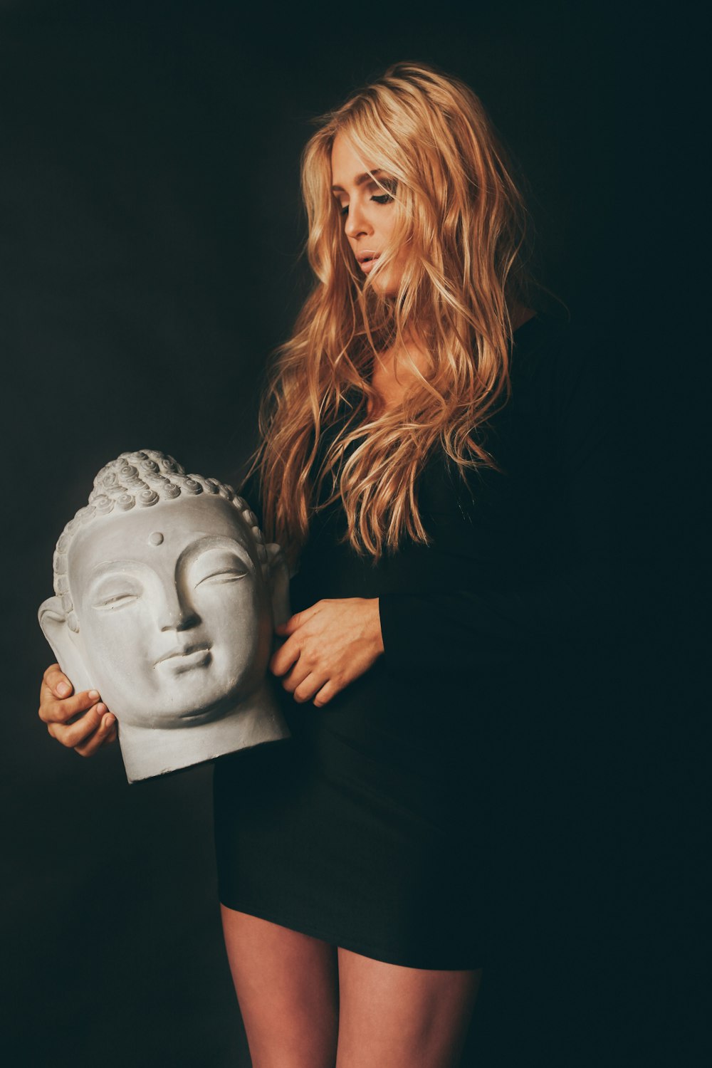 woman holding Gautama Buddha head statue
