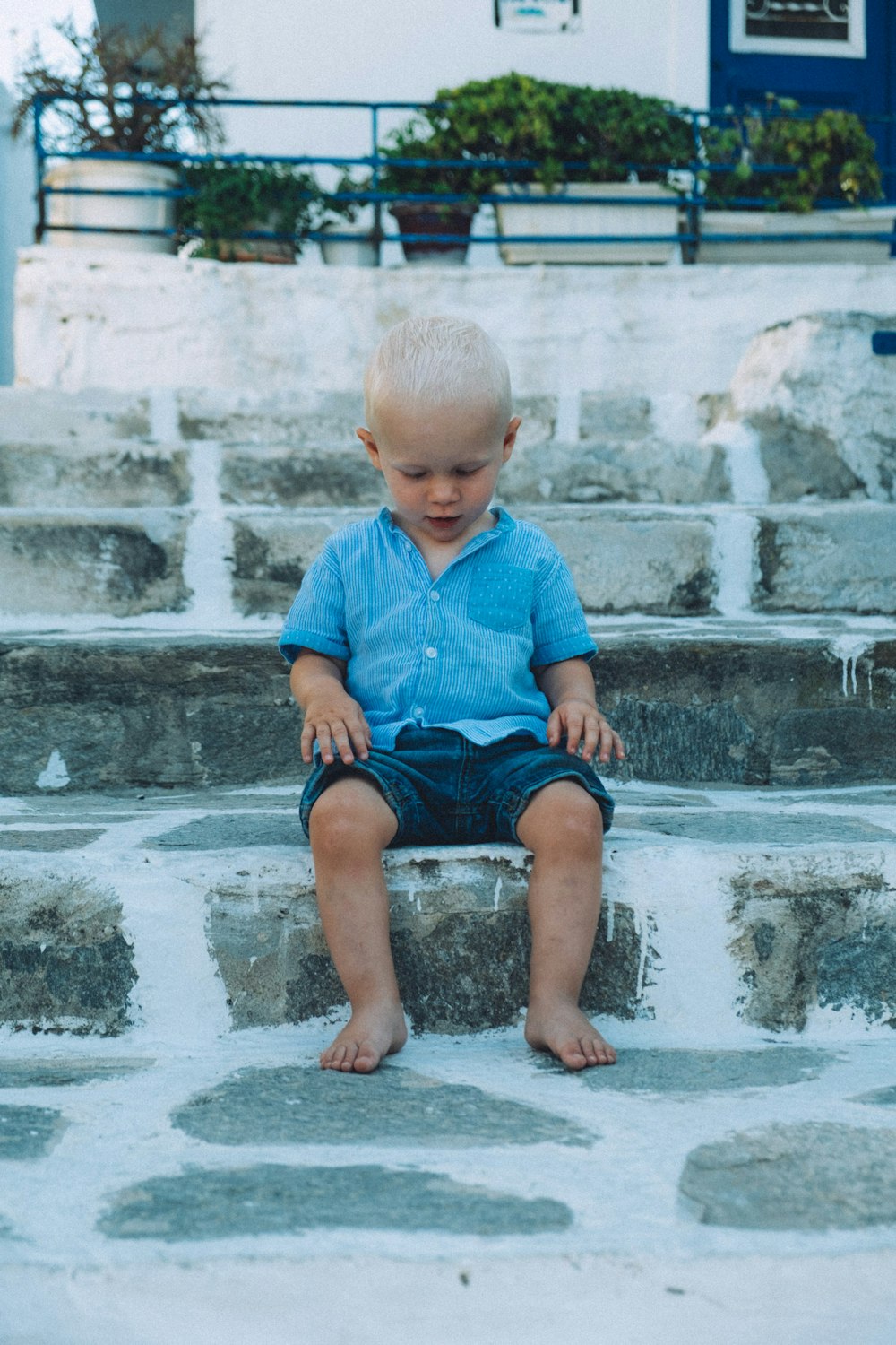 boy sitting on gray concrete stair