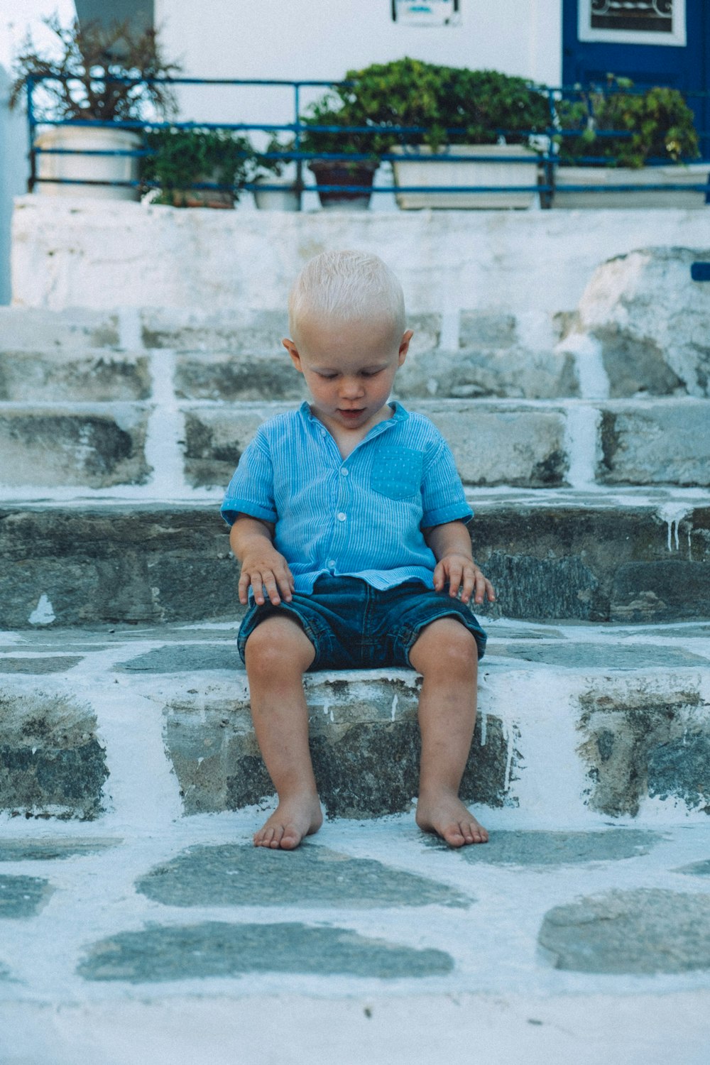 ragazzo che si siede sulla scala di cemento grigio