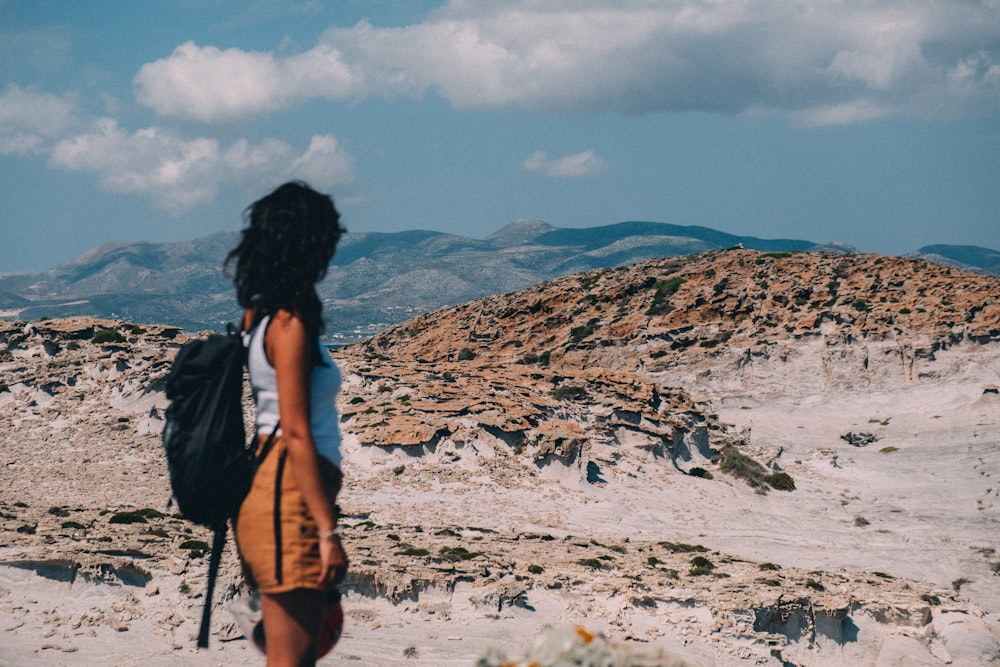 femme debout sur le sable brun sous le ciel bleu pendant la journée