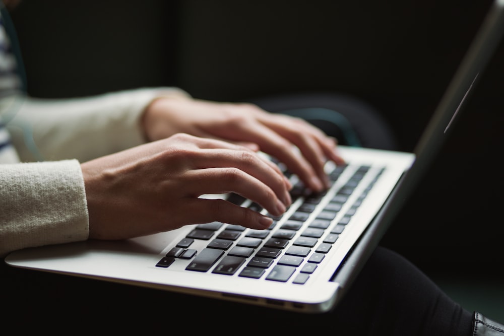 A Person typing with a refurbished Apple Macbook on their lap