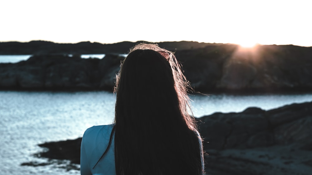 photo of woman in white shirt near body of water