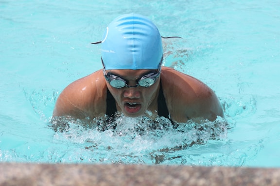 A focused swimmer testing different swimming goggles and gear by the poolside.