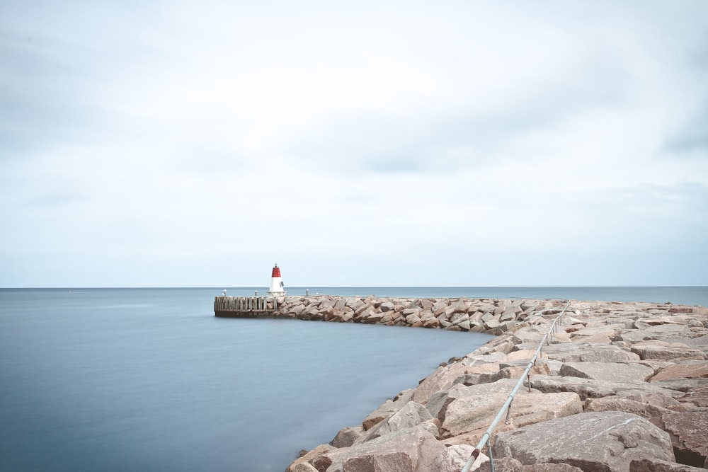 white and red lighthouse near sea at daytime