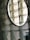 A circular mirror mounted on a wall made of textured glass blocks. The mirror reflects the glass blocks, creating a pattern of geometric shapes and lines, with a subtle play of light and shadow.
