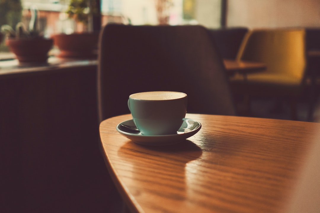 shallow focus photography of teacup with saucer on top of wooden table