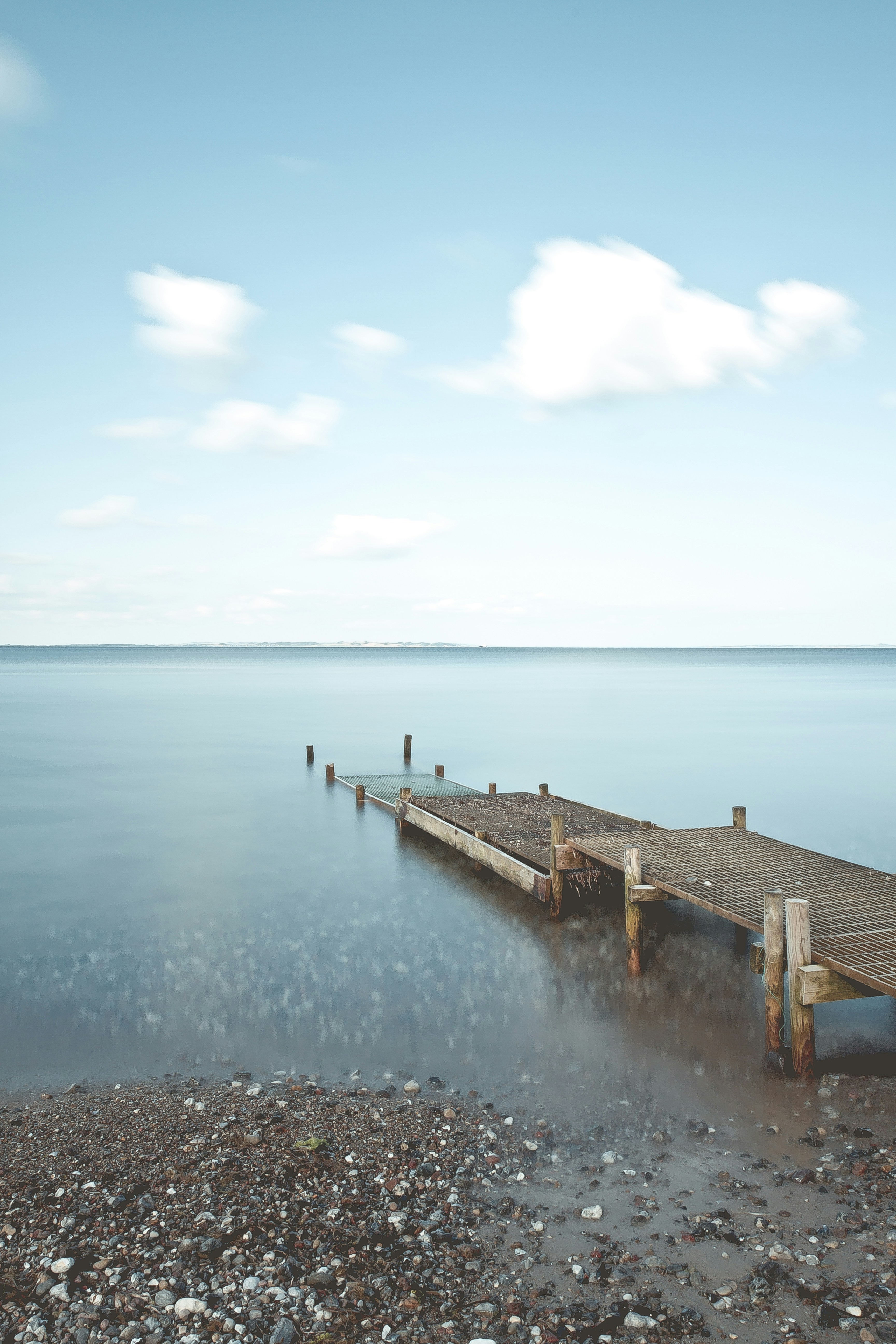 brown metal dock near sea under cloudy sky