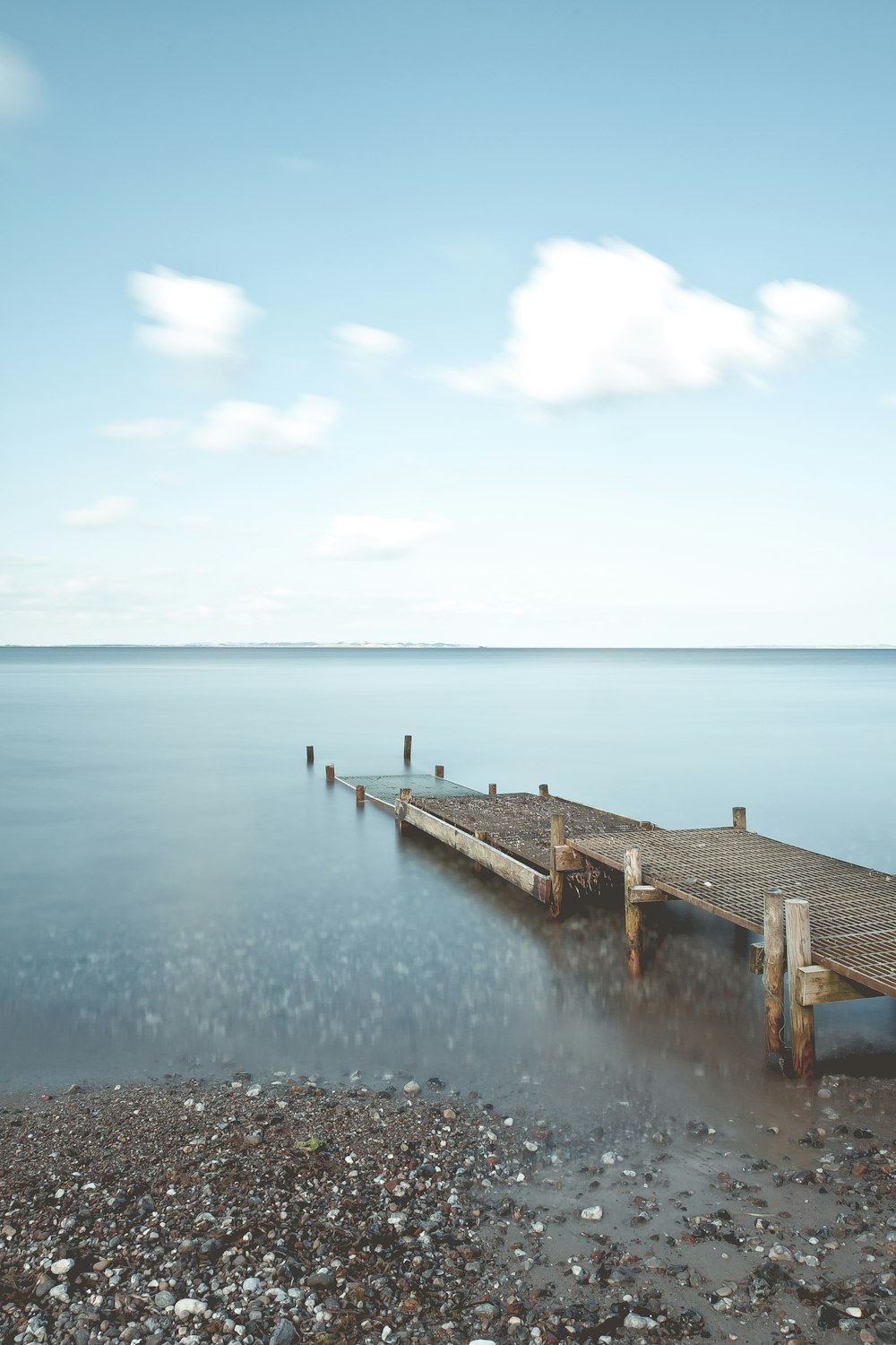 brown metal dock near sea under cloudy sky